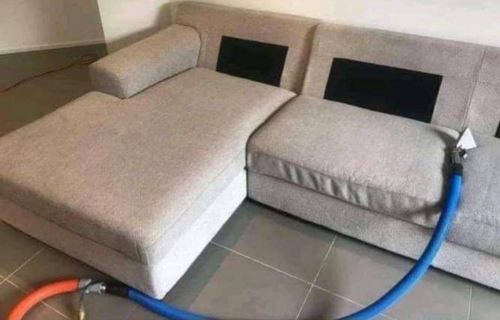 "Expert upholstery cleaning service by Dirt Busters, revitalizing a sofa with advanced cleaning tools."